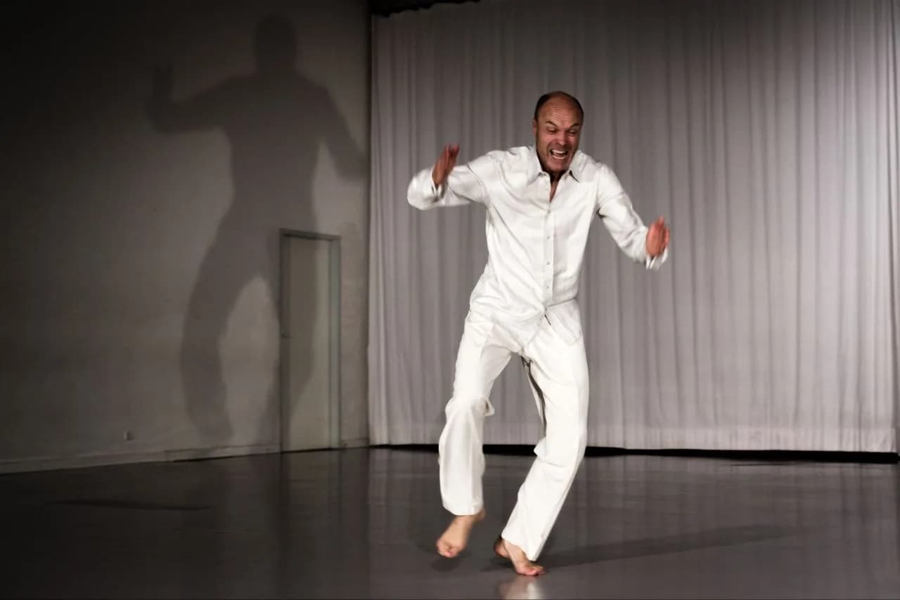 Sten Rudstrøm in Weiß in dynamischer Bewegung, sein Schatten an der Wand